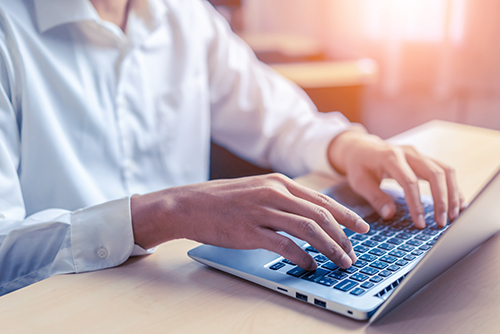 Businessman hand using laptop computer in office.